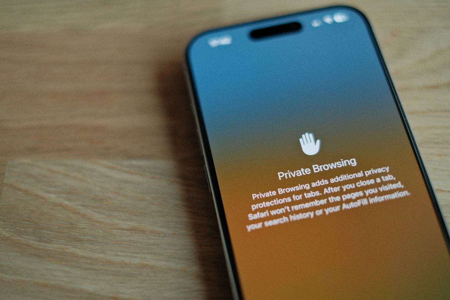 Smartphone displaying private browsing mode on a wooden table.